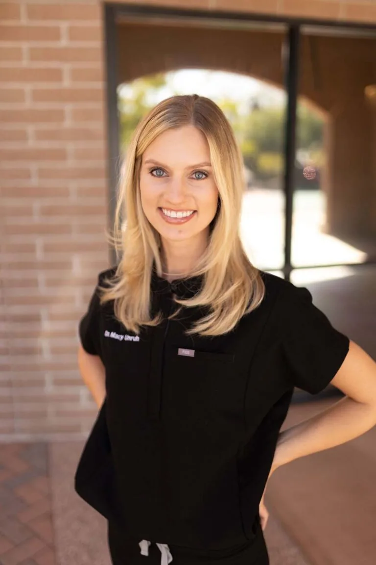 A woman standing in front of a glass and brick wall with both of her hands in the back.