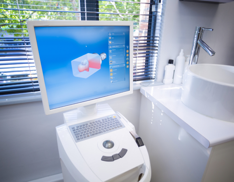A dental CAD/CAM (computer-aided design and computer-aided manufacturing) system in a dental office. The setup includes a computer with a monitor displaying a 3D model of a dental restoration and a milling machine used to fabricate the dental restoration based on the digital design.