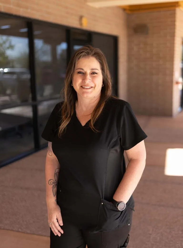 A woman wearing a black scrub standing in a hallway with one of her hand in the pocket.